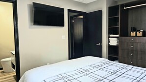 Un dormitorio con cama, armario y televisor.