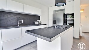 A modern kitchen with white cabinetry, a central island, and a built-in oven.