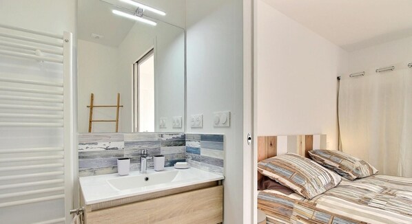 Een moderne badkamer met een witte wastafel, spiegel en betegelde spatwand.