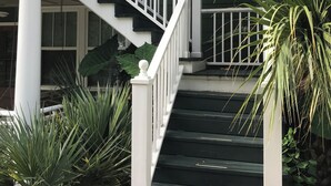 A staircase with white balusters leading to a dark green house. - Above It All. Charming 2-bedroom apartment in the heart of Ocean Springs. (Ocean Springs)