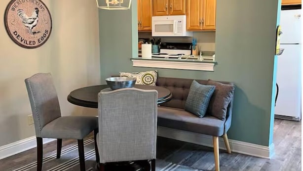 A dining area with a round table, two chairs, a sofa, and a kitchen in the background. - Above It All. Charming 2-bedroom apartment in the heart of Ocean Springs. (Ocean Springs)