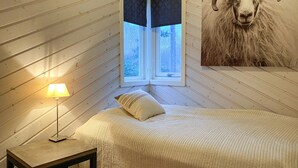 Et hyggeligt værelse med seng, lampe og vindue.