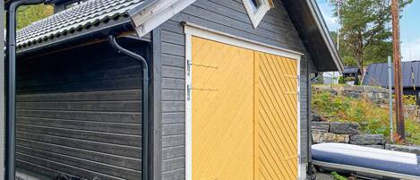 A garage with a yellow door, a black roof, and a small window.