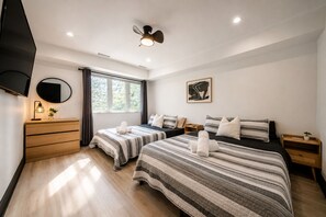 Ein modernes Hotelzimmer mit zwei Betten, einem Flachbildfernseher, einem Deckenventilator und einem großen Fenster.