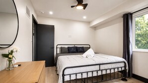 Ein Schlafzimmer mit Bett, Nachttisch und einem fenster mit Vorhängen.