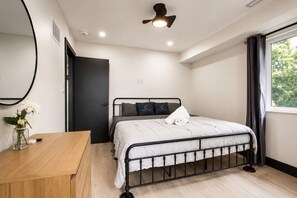 Un dormitorio con cama, mesita de noche y ventana con cortinas.