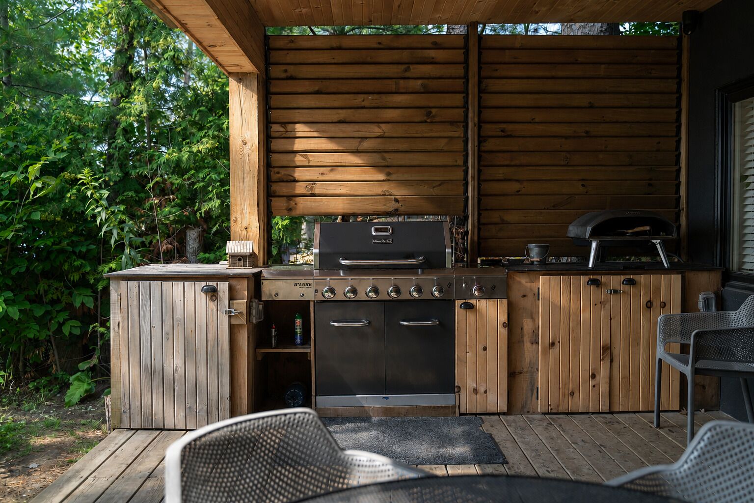 An outdoor wooden deck with a built-in grill station, including a grill, oven, and seating area.