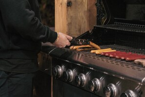 A person grilling sausages and hot dogs on a barbecue grill.