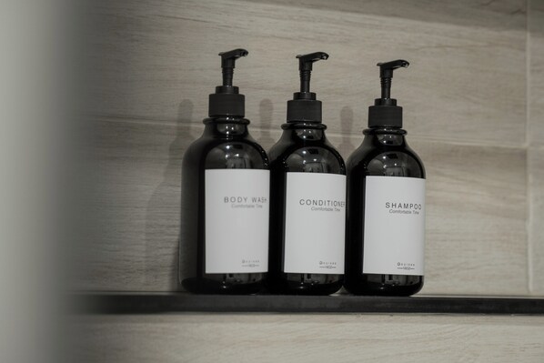Three bottles of body wash, conditioner, and shampoo on a shelf.