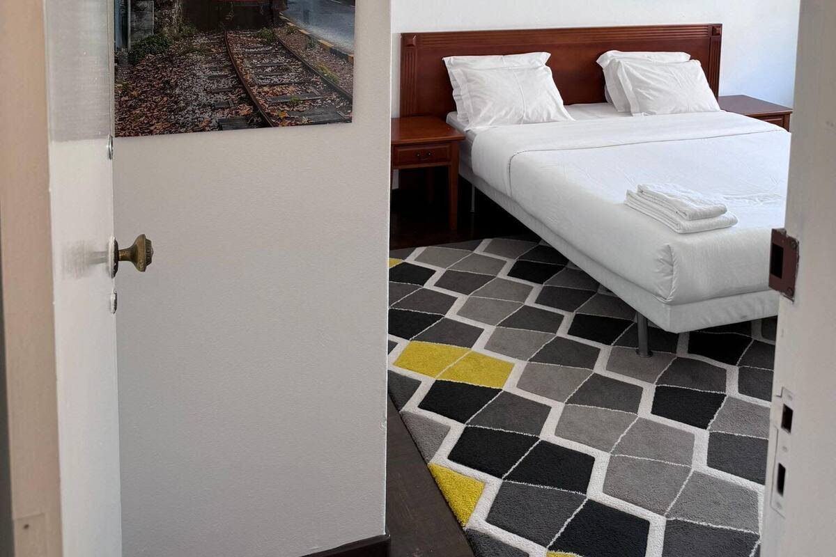 Une chambre d’hôtel avec un lit, une table de chevet, une image d’un tramway et un petit tableau accroché au mur.