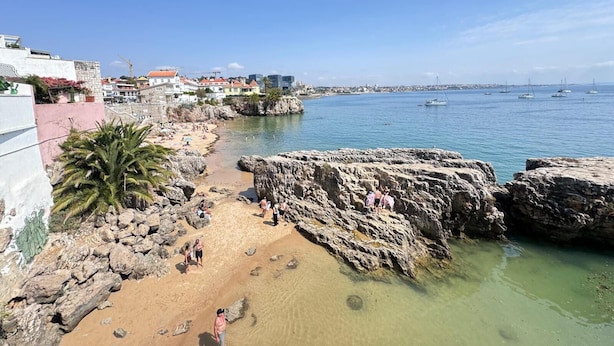 A coastal scene with a rocky beach, clear blue water, and boats. - The Pearl - Cascais Guest House - City & Beach (Cascais)