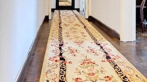 A hallway with a patterned carpet, white walls, and a door at the end. - The Pearl - Cascais Guest House - City & Beach (Cascais)