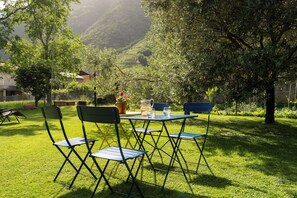 An outdoor seating area with a table and chairs, surrounded by lush greenery and trees.