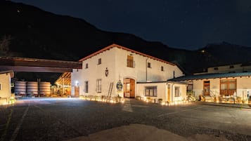 Un edificio con facciata bianca, numerose finestre e tetto rosso. Luci esterne illuminano l'area.
