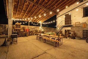 An outdoor patio with a wooden table and benches, surrounded by stone walls and a rustic wooden ceiling. - Perla di Villa – Charming House in Vineyard Estate near the Bernina Express (Villa di Tirano)