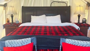 A tented room with a bed, two bedside tables, and lamps.