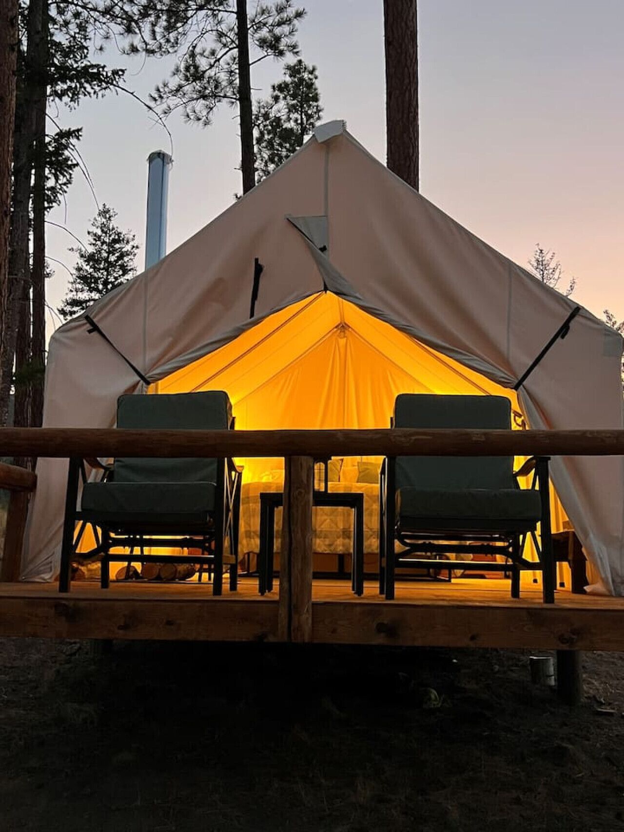 A tent with a table and chairs inside, surrounded by trees.