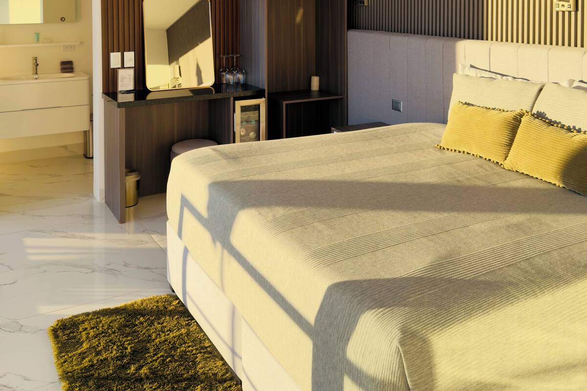 A modern bedroom with a large bed, a wardrobe, a vanity, and a mirror.