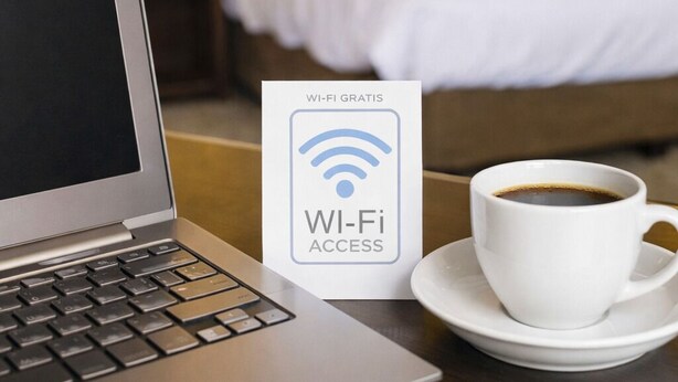 A laptop, a Wi-Fi access sign, and a cup of coffee on a table in a hotel room. - Hotel Luna and Studios 23 Bacalar - Free Bike Rental (Bacalar)