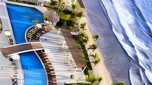 A resort with a large swimming pool, a beach area, and a small circular water feature. - Camino Al Mar (Mazatlán)