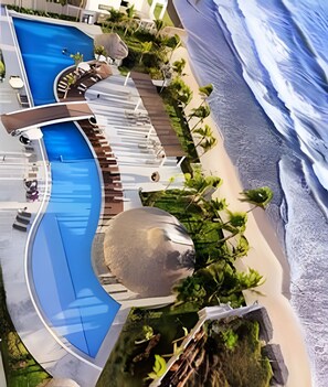 Un complexe hôtelier doté d’une grande piscine, d’une plage et d’un petit bassin circulaire.