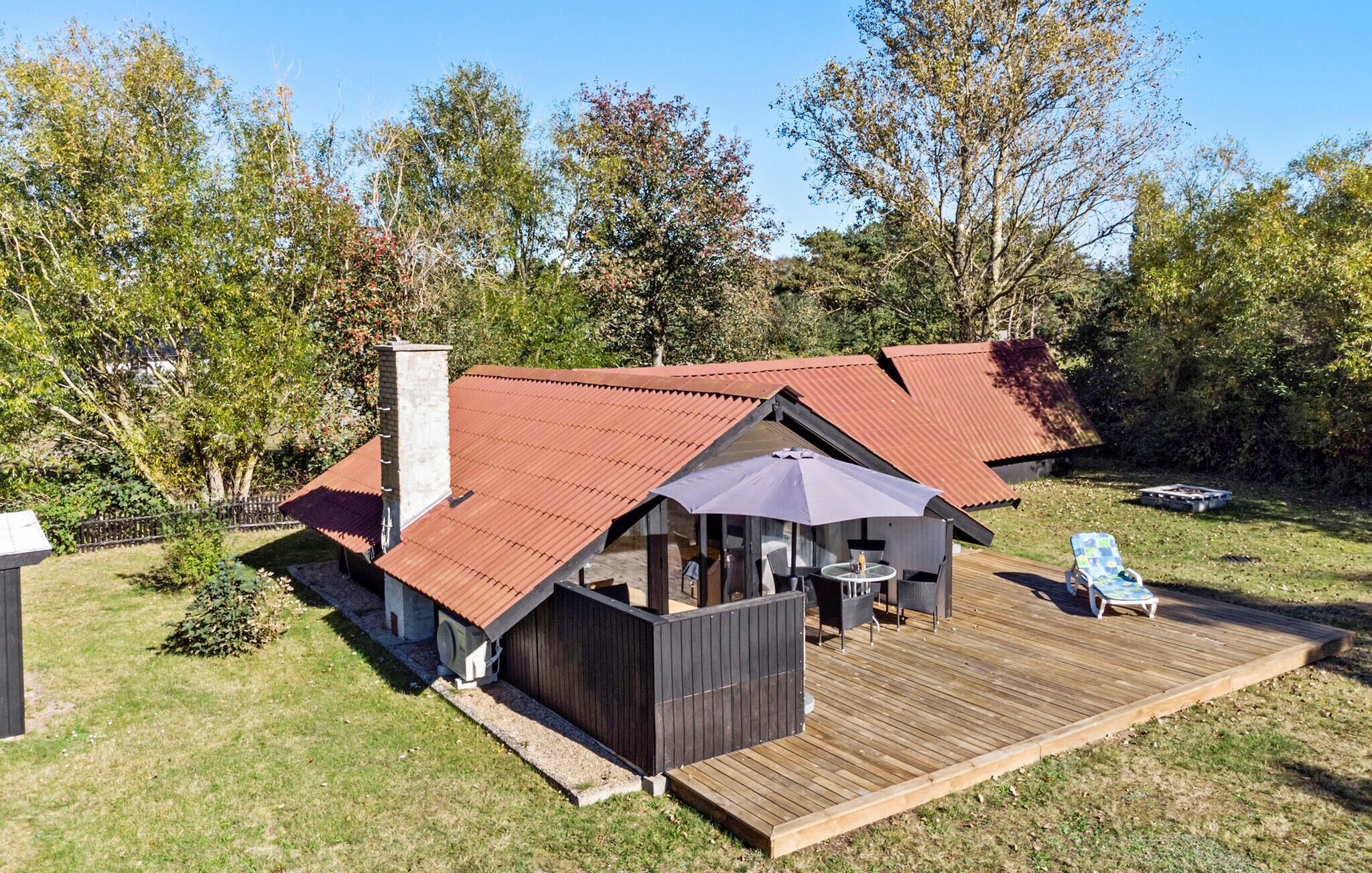 A house with a red roof, a wooden deck, and a patio area with outdoor furniture.