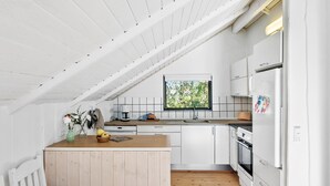 A modern kitchen with white cabinetry, a wooden countertop, and a window with a view of greenery.