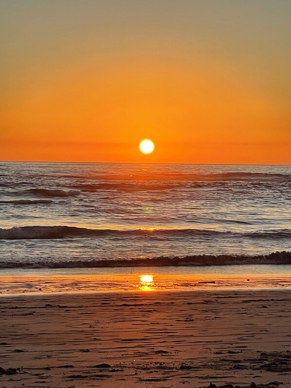 Ein Sonnenuntergang über einem Strand mit Wellen.