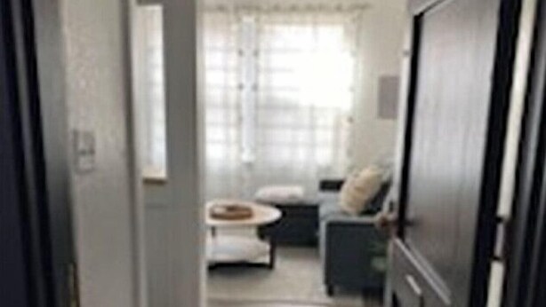 A narrow hallway leading to a living area with a sofa and a small table. - The Suites at The George 212 (Klamath Falls)
