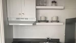 A kitchen with white cabinets, a stove, a sink, and a refrigerator. - The Suites at The George 212 (Klamath Falls)
