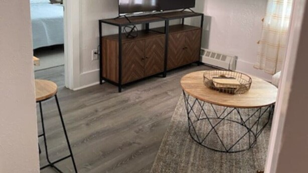 Un saló modern amb televisió de pantalla plana, un moble de fusta amb disseny d'espiga, una taula de centre rodona amb cistella teixida i una catifa gris.