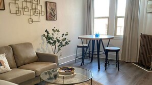 A living room with a sofa, coffee table, and a dining area with a table and chairs. - The George 316 an Art Deco Escape (Klamath Falls)