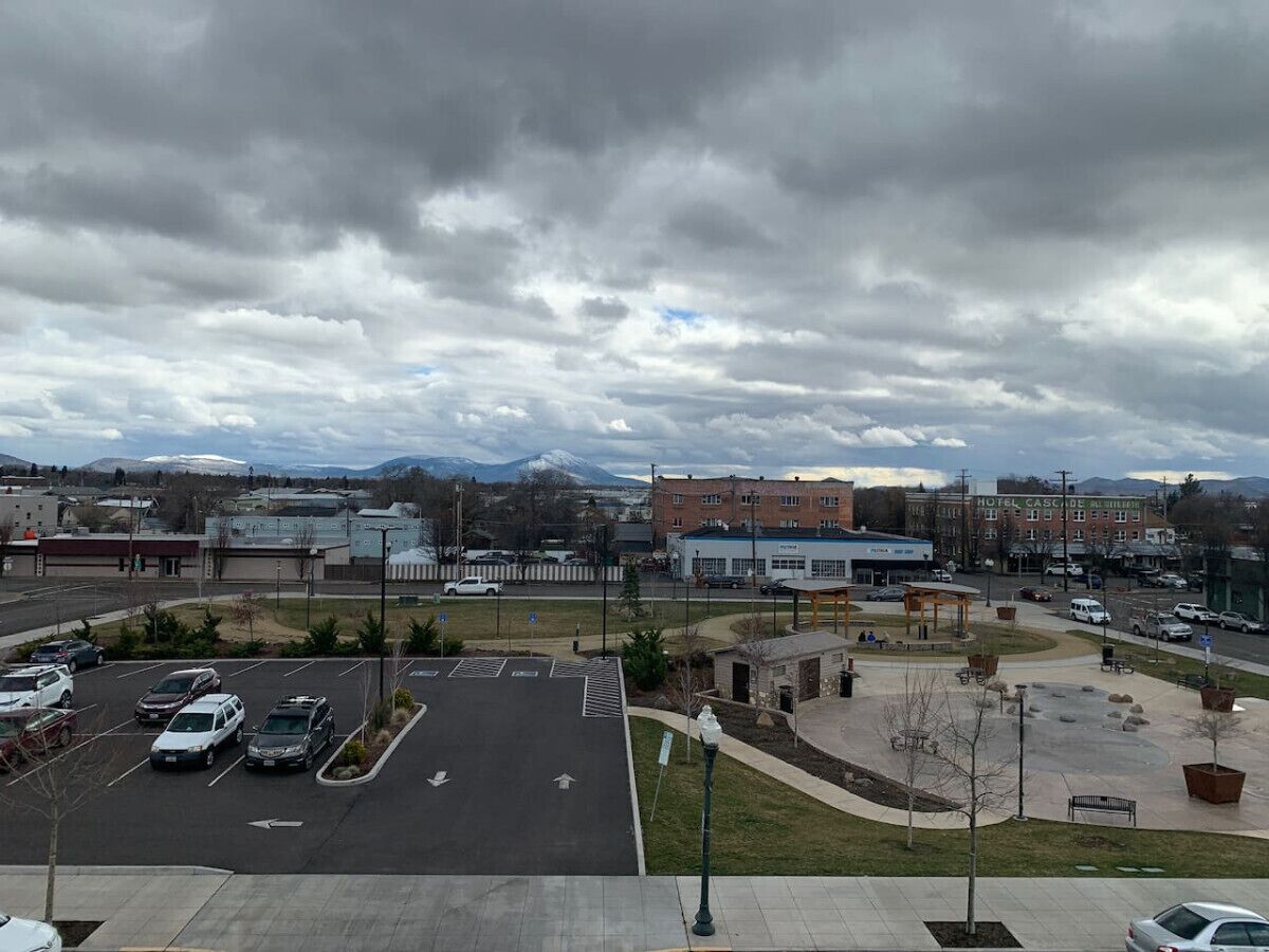 A parking lot with several cars, a building labeled "Hotel Cascade Mountain Resort," and a mountainous background.