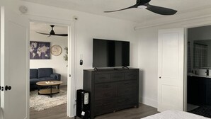Une chambre à coucher comprenant un lit, une commode, un téléviseur et un ventilateur de plafond.