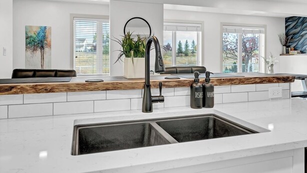 A modern kitchen with a white countertop, black faucet, and pendant lights.