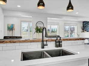 Une cuisine moderne avec un plan de travail blanc, un robinet noir et des luminaires suspendus.