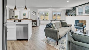A modern kitchen with white cabinets, a stainless steel dishwasher, and pendant lighting.