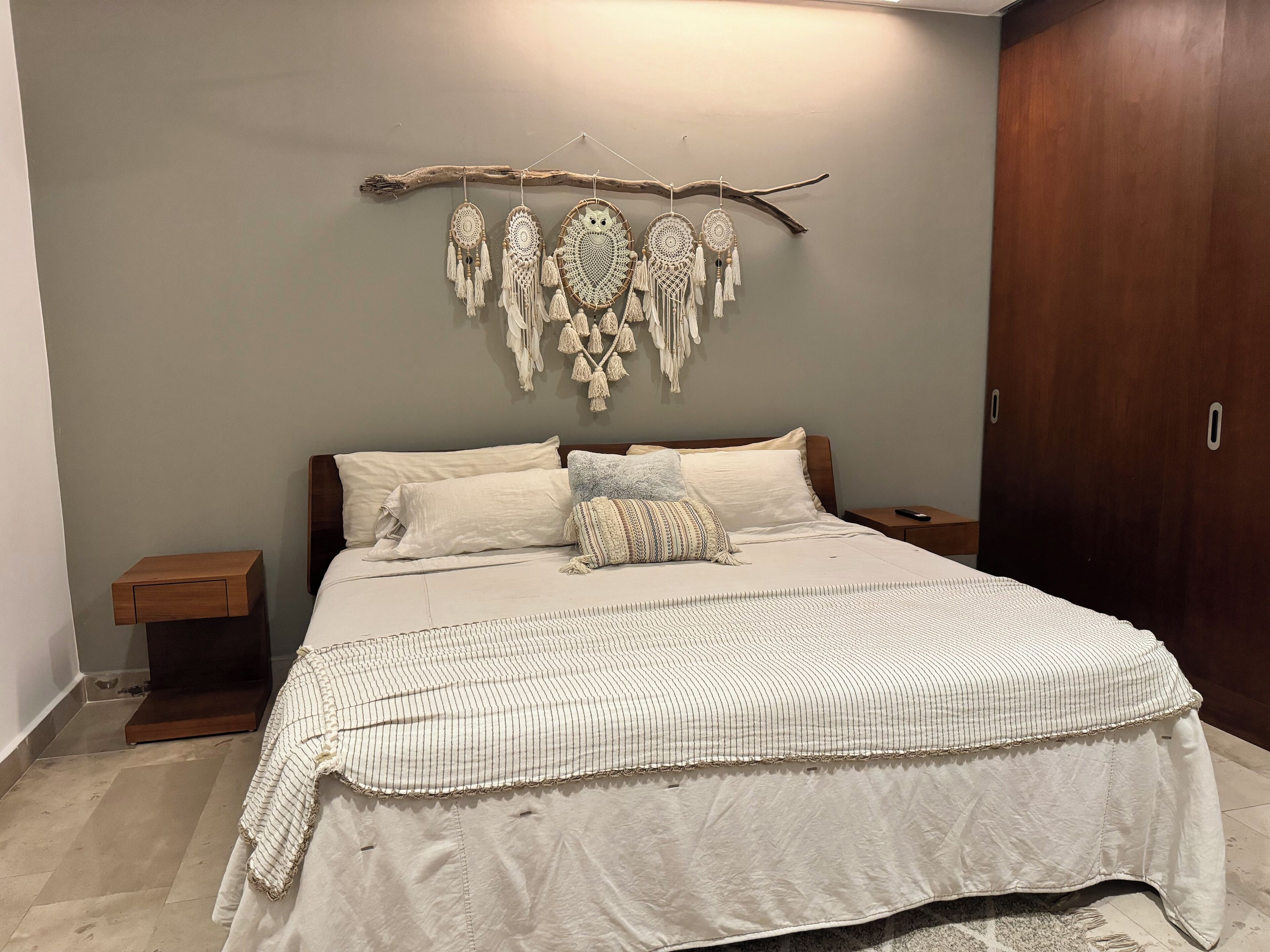 Un dormitorio con cama, mesita de noche, armario y un adorno en la pared.