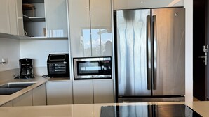 Eine moderne Küche mit einem Edelstahl-Kühlschrank, einem eingebauten Backofen und einer Kaffeemaschine.