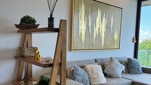 Ein modernes Wohnzimmer mit einem grauen Sofa, dekorativen Kissen und einem Holzleiterregal mit verschiedenen Gegenständen.