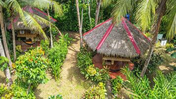 A tropical resort with thatched-roof huts surrounded by lush greenery.