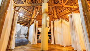 A room with a wooden ceiling and a large pillar in the center. There is a bed with white curtains and a mattress. - Water To Forest Ecolodge (Loboc)