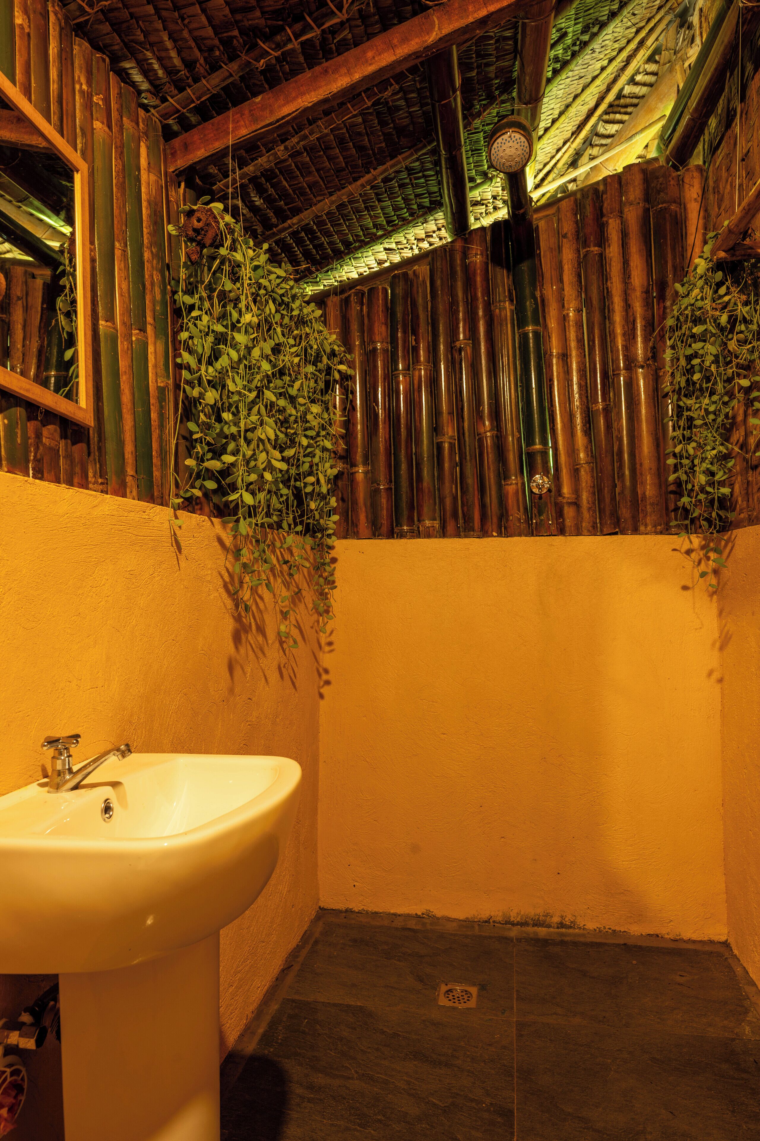 A bathroom with a white sink, bamboo walls, and a shower area.