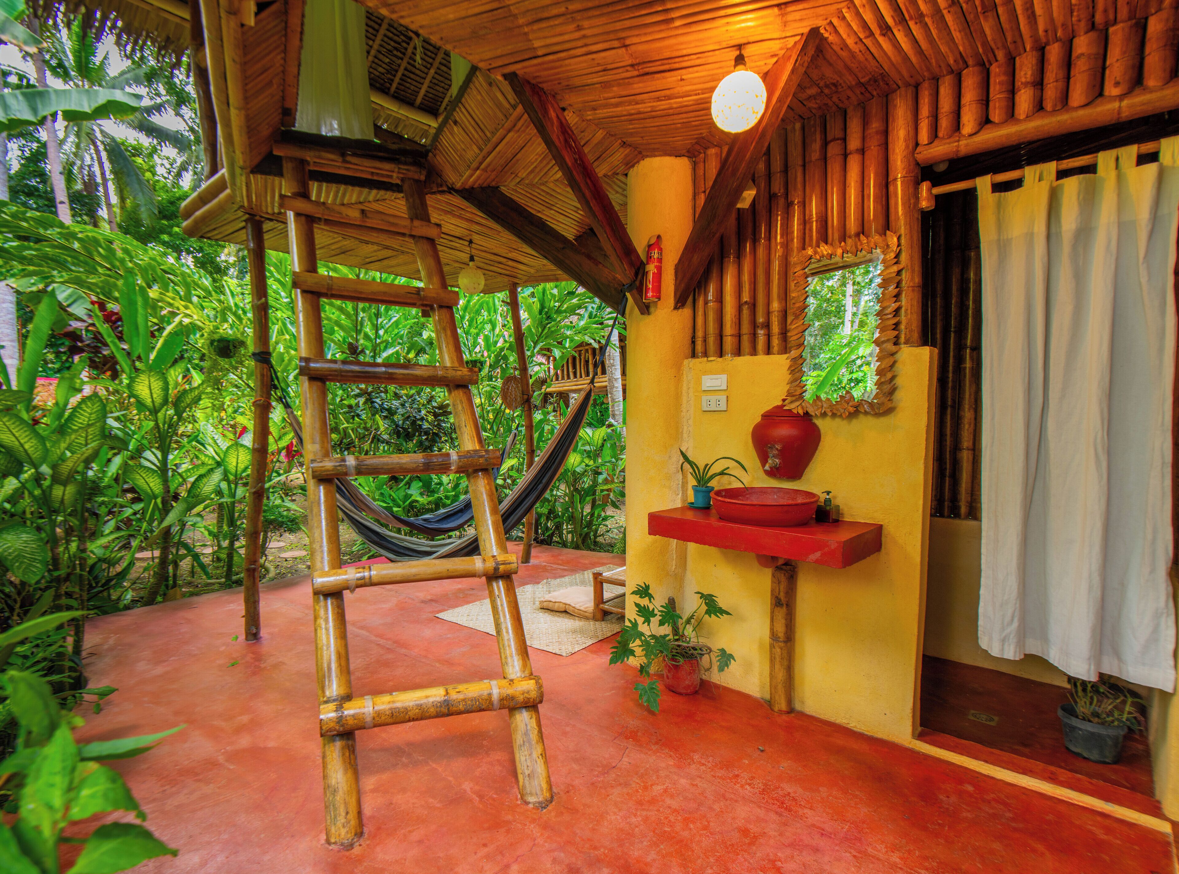 A room with a hammock, a red sink, and a potted plant.