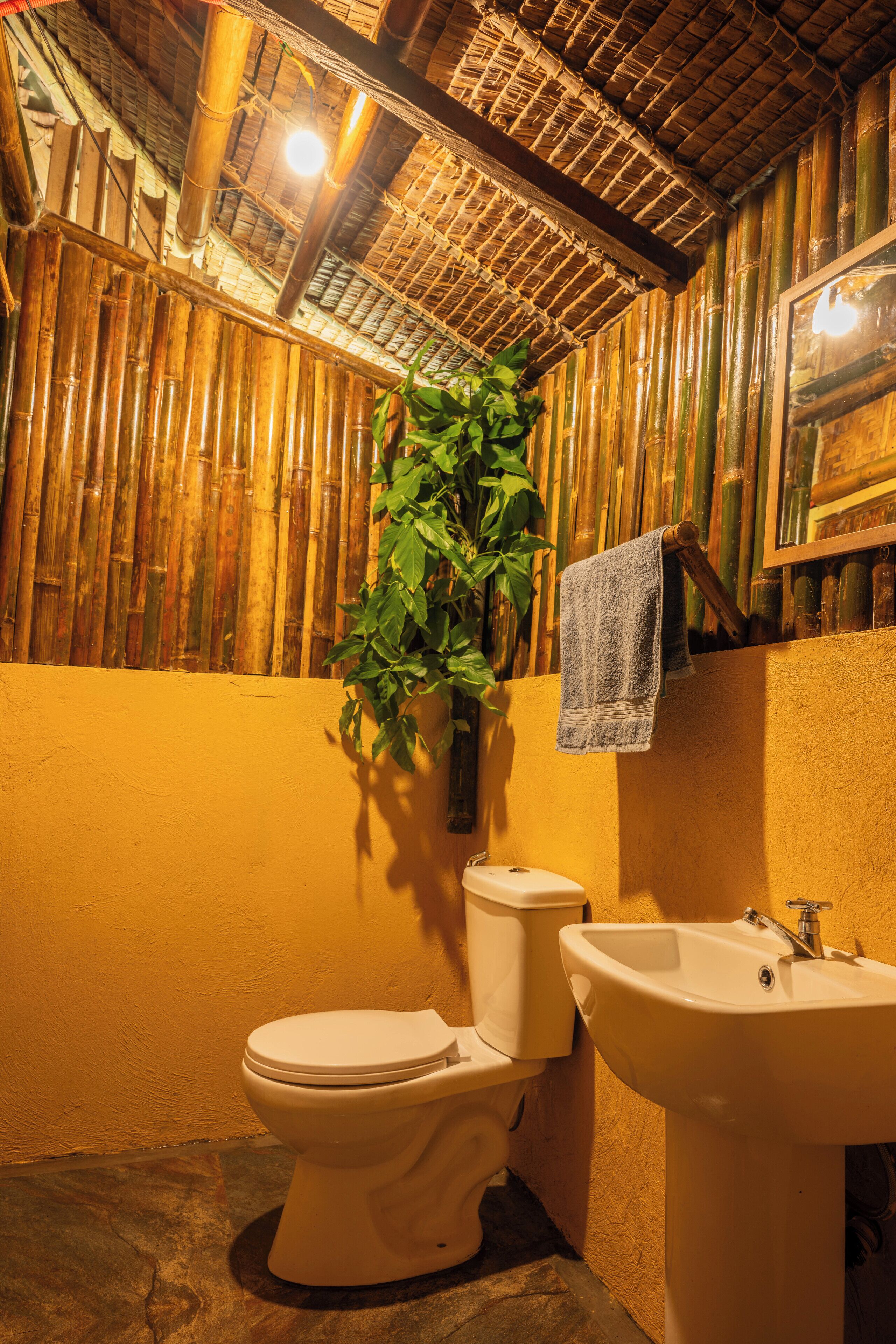 Une salle de bain avec un mur en bambou, des toilettes et un lavabo.