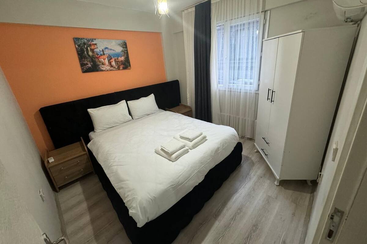 Un dormitori amb un llit, una tauleta de nit, un armari i un quadre a la paret.