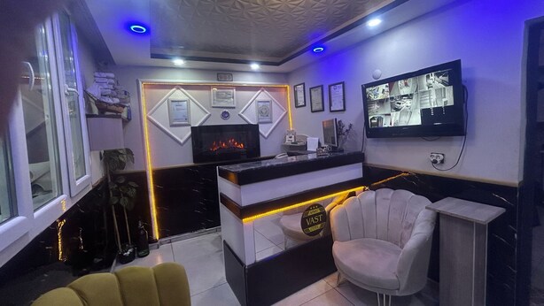 A modern reception area with a fireplace, a television mounted on the wall, and a seating area with a chair. - Vast Apart Otel (Izmir)