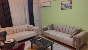 A living room with two sofas, a coffee table, and a dining table with chairs. - Vast Apart Otel (Izmir)