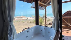 Una habitación con una bañera grande, techo de madera y vista al océano.