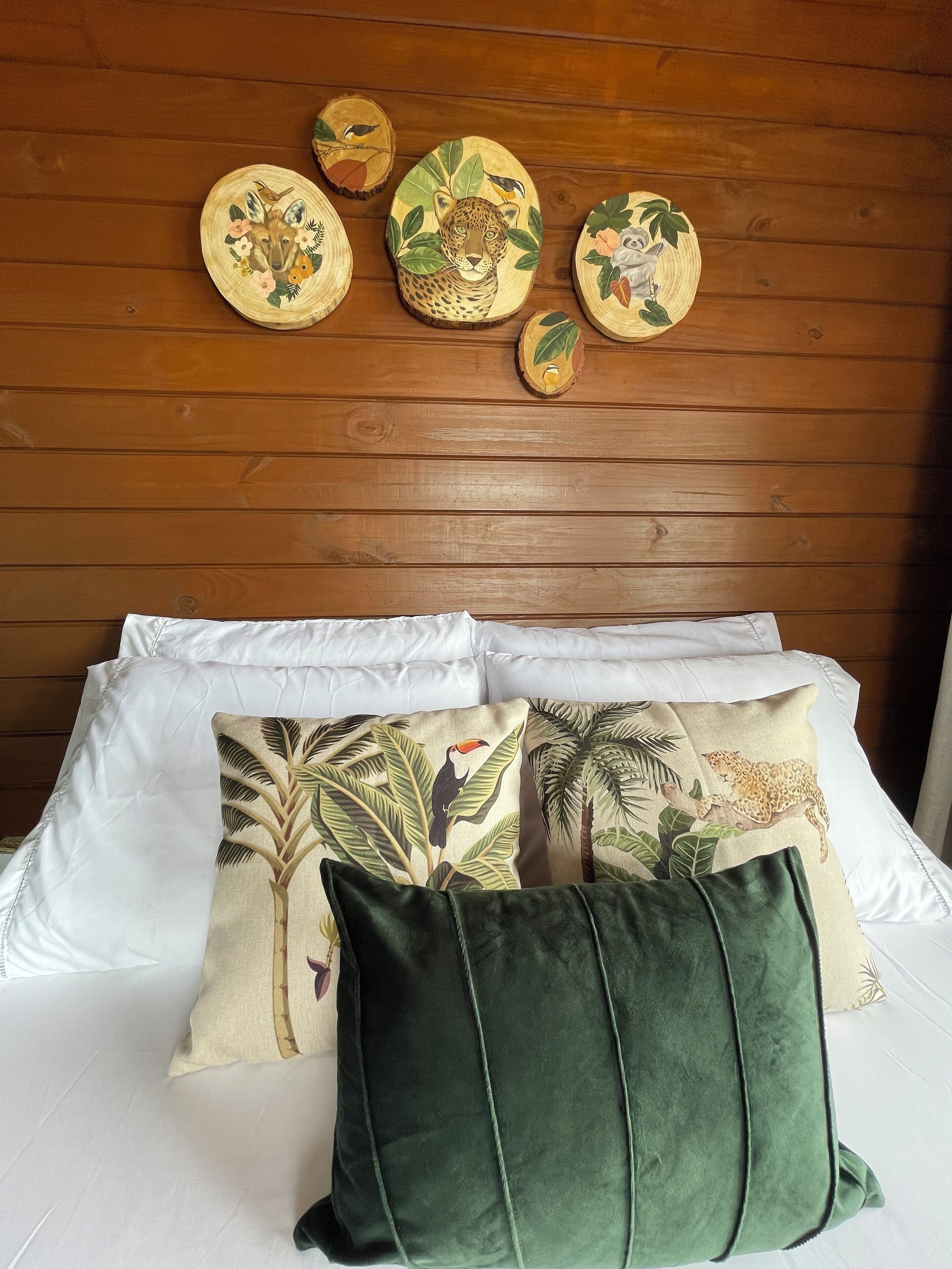 Una cama con ropa blanca de cama y almohadones decorativos con estampados de jungla y animales.